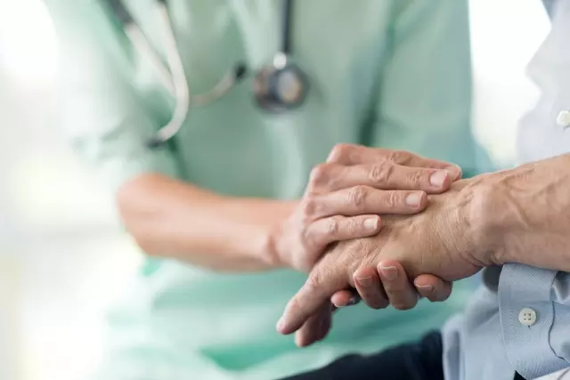 Caregiver and senior holding hands