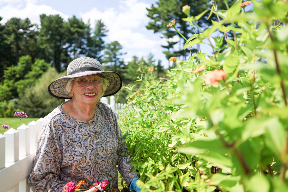 Resident Barbara Roberts smiles from the lush garden on The Commons in Lincoln campus