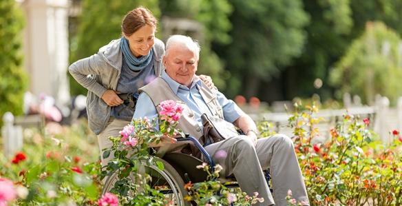Woman pushing senior man in wheelchair outdoors