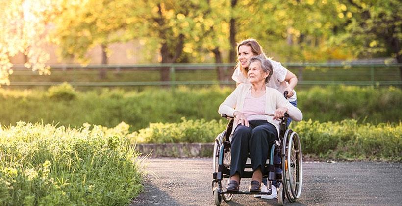 Young woman pushing senior woman in wheelchair