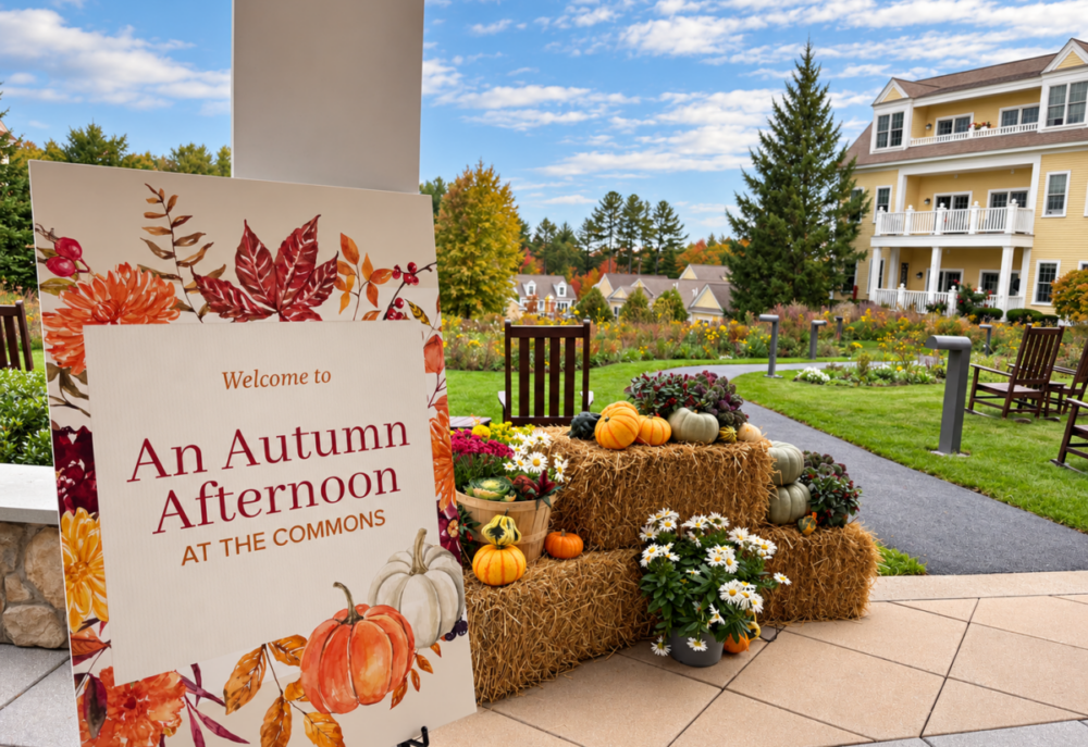 An autumn welcome display at The Commons features pumpkins, hay bales and colorful flowers overlooking landscaped gardens and residential buildings.
